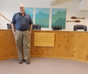 Steve Giesbrecht stands in front of the Borough of Petersburg logo in the Assembly chambers. (Joe Sykes)