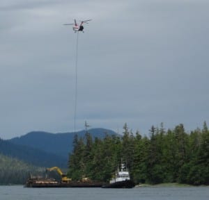 A helicopter loads a log onto a barge during a University of Alaska timber sale on western Mitkof Island in 2014 (KFSK file photo)